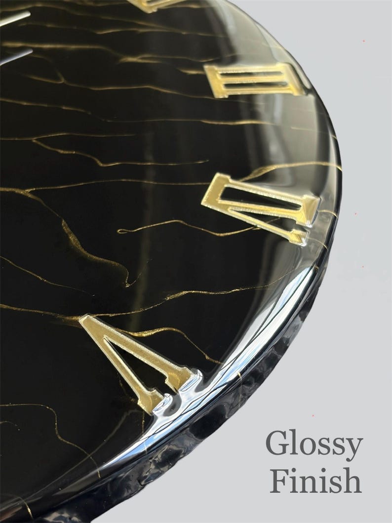 May include: Close-up of a black clock face with gold Roman numerals and gold veining. The clock has a glossy finish, with the words "Glossy Finish" in the lower right corner.