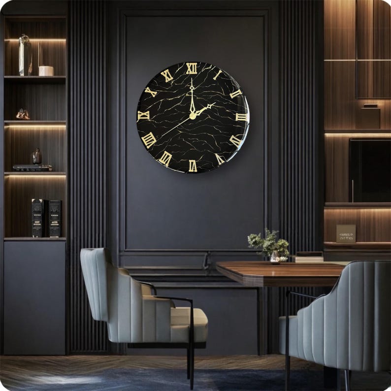 May include: A large, round wall clock with a black marble-effect face and gold Roman numerals. The clock is mounted on a dark gray wall, with a modern interior design theme. The clock's hands are gold, and the overall aesthetic is elegant and sophisticated.