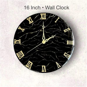 May include: A 16-inch wall clock with a black marble design and gold Roman numerals. The clock hands are gold, and the face has a glossy finish. The text "16 Inch &bull; Wall Clock" is at the top.