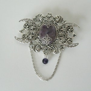 May include: Silver triple moon pendant with a purple stone and a dangling purple bead.