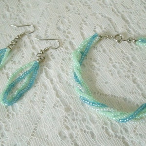 May include: A set of turquoise and light green beaded earrings and a matching bracelet. The jewelry is made with small seed beads and has a delicate, feminine look.