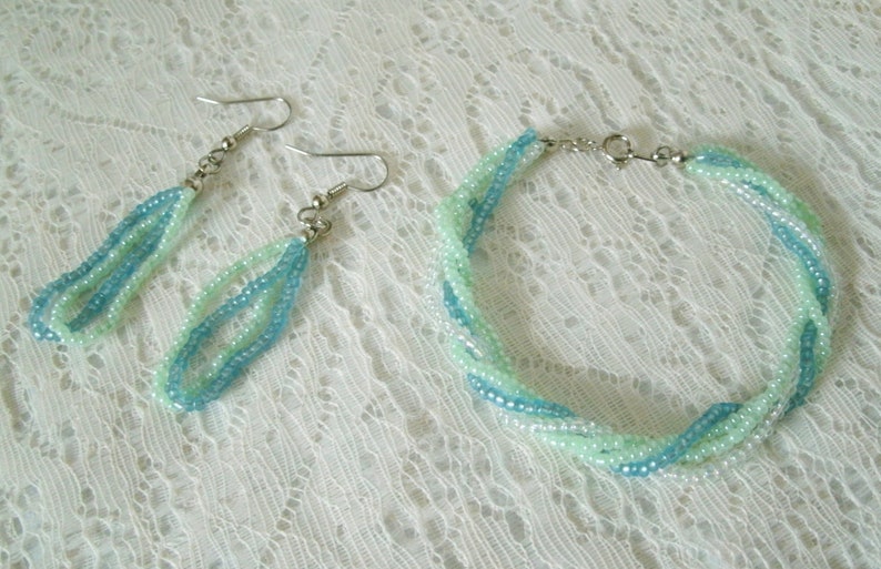 May include: A set of turquoise and light green beaded earrings and a matching bracelet. The jewelry is made with small seed beads and has a delicate, feminine look.