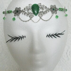 Puede incluir: Diadema de hoja de plata y verde con una gran piedra preciosa verde en el centro. La diadema est&aacute; decorada con peque&ntilde;as cuentas verdes y tiene un detalle de cadena.