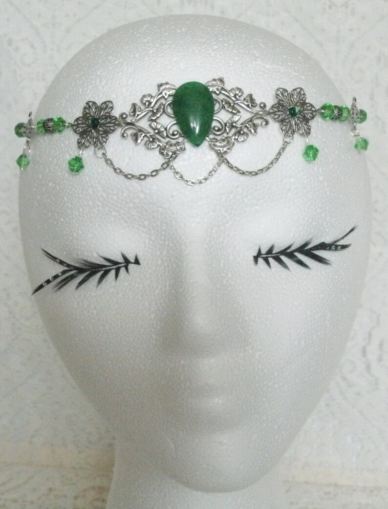 Puede incluir: Diadema de hoja de plata y verde con una gran piedra preciosa verde en el centro. La diadema est&aacute; decorada con peque&ntilde;as cuentas verdes y tiene un detalle de cadena.