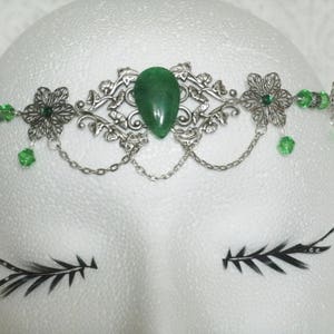 Puede incluir: Diadema de plata con una piedra preciosa verde y cuentas de vidrio verdes. La diadema tiene un dise&ntilde;o floral.