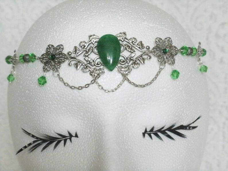 Puede incluir: Diadema de plata con una piedra preciosa verde y cuentas de vidrio verdes. La diadema tiene un dise&ntilde;o floral.