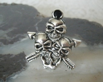Puede incluir: Encanto de plata con tres cabezas de calavera con detalles de flecha. Las calaveras están apiladas una encima de la otra, con la calavera superior mirando hacia adelante y las dos inferiores mirando hacia los lados. El encanto es una gran adición a cualquier colección de joyas.