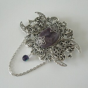 May include: A silver filigree pendant with a purple gemstone and a silver chain.