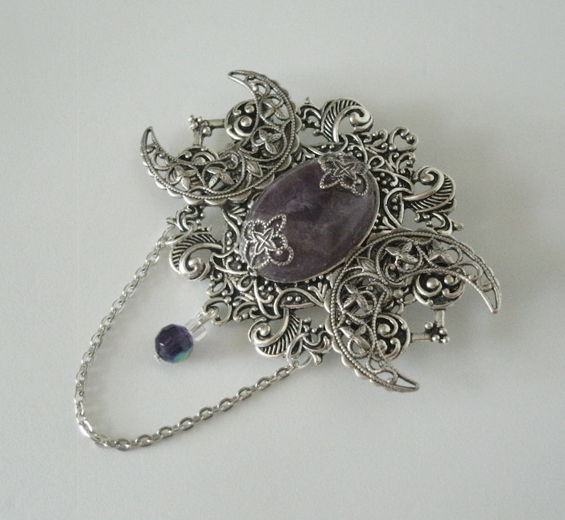 May include: A silver filigree pendant with a purple gemstone and a silver chain.