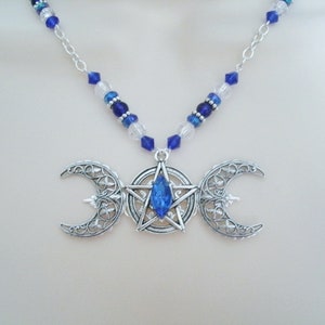 May include: A silver necklace with a triple moon pendant featuring a blue crystal star in the centre. The necklace is made with blue and clear glass beads.