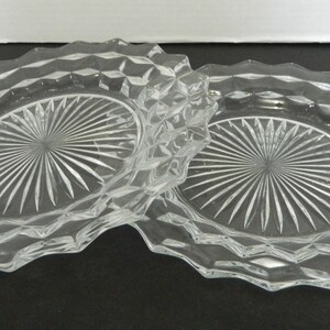 K&ouml;nnte beinhalten: Zwei klare Glasplatten mit einem rautenf&ouml;rmigen Muster an den R&auml;ndern und einem Sternmuster in der Mitte. Die Platten sind oval und scheinen aus der Vintage-&Auml;ra zu stammen.