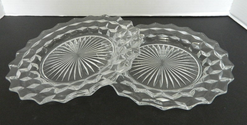 K&ouml;nnte beinhalten: Zwei klare Glasplatten mit einem rautenf&ouml;rmigen Muster an den R&auml;ndern und einem Sternmuster in der Mitte. Die Platten sind oval und scheinen aus der Vintage-&Auml;ra zu stammen.