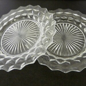 K&ouml;nnte beinhalten: Zwei klare Glasplatten mit einem rautenf&ouml;rmigen Muster an den R&auml;ndern. Die Mitte jeder Platte weist ein Sonnenstrahl-Design auf. Die Platten bestehen aus klarem Glas.