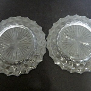 K&ouml;nnte beinhalten: Zwei klare Glasplatten mit einem strukturierten, geometrischen Design am Rand und einem radialen Muster in der Mitte. Die runden Teller eignen sich zum Servieren von Speisen oder als dekorative Elemente.