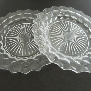 K&ouml;nnte beinhalten: Zwei Servierschalen aus klarem Glas. Jede Schale hat einen gewellten Rand und ein Rautenmuster am Rand. Die Mitte jeder Schale weist ein Sternmuster auf. Die Schalen sind durch einen Griff verbunden.