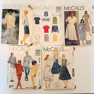 May include: A collection of vintage McCall's sewing patterns. The patterns feature illustrations of various clothing items, including dresses, tops, and jackets. The patterns are in various sizes and styles, with text indicating the pattern numbers and brands.