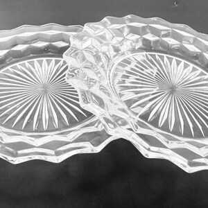 K&ouml;nnte beinhalten: Klarer Servierteller aus Glas mit zwei ovalen F&auml;chern. Der Teller hat ein rautenf&ouml;rmiges Muster an den R&auml;ndern und ein Sternmuster in der Mitte jedes Fachs. Der Griff ist ebenfalls rautenf&ouml;rmig.