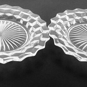 K&ouml;nnte beinhalten: Zwei klare Glasplatten mit einem Sternmuster in der Mitte und einem rautenf&ouml;rmigen Rand. Die Teller haben einen gewellten Rand und liegen auf einer dunklen Oberfl&auml;che. Diese Vintage-Teller eignen sich zum Servieren von Vorspeisen oder Desserts.