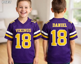 Pode incluir: Uma camisa de futebol americano roxa com o texto VIKINGS e o número 18 em amarelo na frente, e o nome DANIEL com o número 18 em amarelo nas costas. As mangas têm listras brancas e amarelas. O texto diz CUSTOM ANY REQUEST.