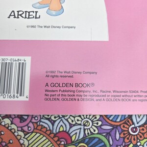 May include: A vintage Golden Book with a pink cover, featuring Ariel from The Little Mermaid. The illustration shows Ariel's legs and the name "ARIEL". Published in 1992, it's a "GOLDEN BOOK" from The Walt Disney Company.