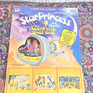 May include: A vintage "Star Princess and Pluta" paper doll playbook. The cover features a spaceship illustration with the text "North Star Space Base." The book includes press-out space clothes and a command center.