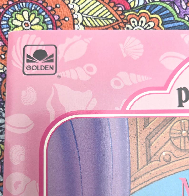 May include: Pink book cover featuring seashell illustrations and the Golden logo. The cover has a white border and a purple section. The background is a colourful floral pattern.