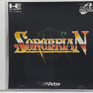 May include: A Super CD-ROM System game case for Sorcerian. The game title is in a yellow and orange font with a black background. The case has the HE System PC Engine logo and the Victor logo.