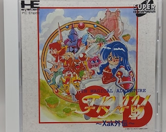 Puede incluir: Un cartucho de videojuego para el Super CD-ROM System, con una ilustración colorida de un personaje femenino con cabello azul y un vestido rojo, rodeado de varias criaturas fantásticas. El título del juego es "Xak", con el subtítulo "In Magical Adventure".