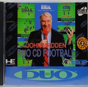 May include: A CD case for the video game "John Madden Duo CD Football." The cover features a smiling man holding a microphone, with a football field graphic and the game's title in large text. The case is in a clear plastic jewel case.