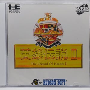 May include: A CD case for the Super CD-ROM System video game "The Legend of Heroes II". The case features a yellow and gold background with a crest and the game title in Japanese and English. The game is published by Hudson Soft.