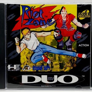 May include: A Riot Zone Super CD-ROM System video game case. The cover features two action figures in a fighting pose, with the game title in a red and blue design. The game is labeled as an action game.