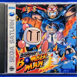 May include: Sega Saturn video game case for Saturn Bomberman. The cover art features a cartoon character with a white face and a blue and white outfit. The background is a mix of blue, orange, and yellow with other cartoon characters and the game's title.