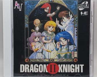 Puede incluir: Una caja de juego Super Famicom para el videojuego Dragon II Knight. La caja presenta una ilustración colorida de cinco personajes en un entorno de fantasía. El texto "Dragon II Knight" está impreso en blanco sobre un fondo negro.