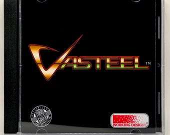 Puede incluir: Una caja de CD negra con el título del juego "Vasteel" en naranja y verde. La caja incluye logotipos de "Turbo Grafx" y "Working Designs". El CD está en una caja de plástico transparente.