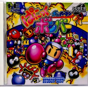 May include: A Super Bomberman PC Engine CD-ROM game case. The cover features a colorful illustration of the Bomberman character with other cartoon characters and Japanese text. The Hudson Soft logo is at the bottom.