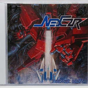 May include: A video game cover featuring a red and black robot with the word "NEXCR" in blue and white letters. The text "maxat soft" is in blue letters at the bottom of the cover.