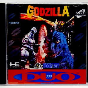 May include: A Godzilla video game case featuring a blue Godzilla and a silver robot-like creature. The title "GODZILLA" is in yellow and orange, with the word "FIGHTING" below. The case has a red and blue DUO logo.