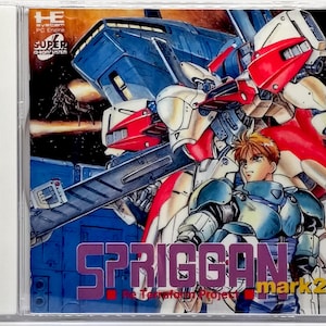 May include: A Spriggan Mark 2 PC Engine Super CD-ROM System game case. The cover art features a mecha robot and a young man in armor. The title is in purple and the background is blue.