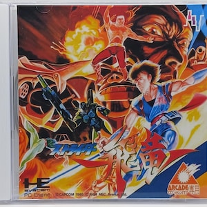 May include: A video game CD case featuring a colorful illustration of characters and a robot. The title of the game is "X-MAPP", and the text "Arcade" is visible in the lower right corner.