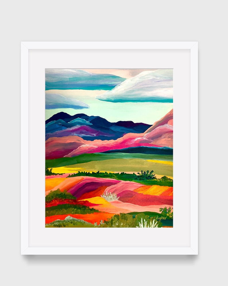 Puede incluir: Pintura de paisaje enmarcada con borde blanco. La obra representa una colorida escena de colinas y monta&ntilde;as en tonos rosa, naranja, verde y azul. El cielo presenta nubes blancas y esponjosas sobre un fondo azul claro.