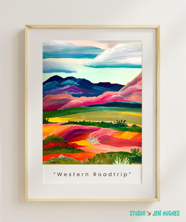 Puede incluir: L&aacute;mina art&iacute;stica enmarcada con una pintura de paisaje colorida. La obra de arte representa colinas onduladas en tonos rojos, rosas, verdes y amarillos, con monta&ntilde;as azules y un cielo nublado. El texto "Western Roadtrip" est&aacute; impreso en la parte inferior.