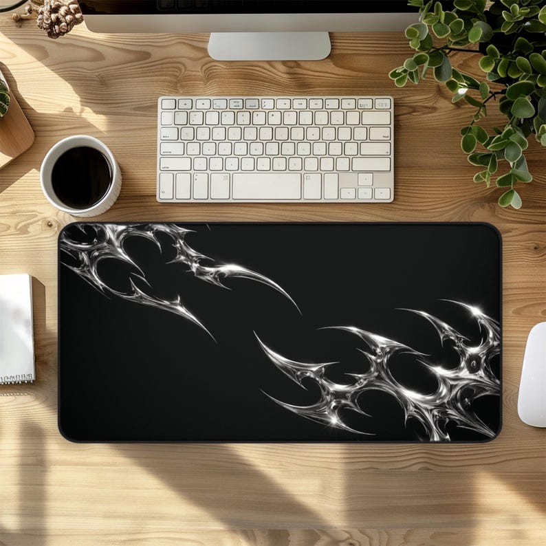 Black abstract desk mat featuring sharp chrome metallic shapes on a deep black background, designed as a large extended mouse pad for modern gaming and work setups