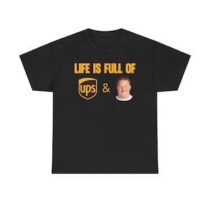 May include: Black t-shirt featuring the text "LIFE IS FULL OF UPS &" in yellow, alongside a person's image and the UPS logo in yellow.