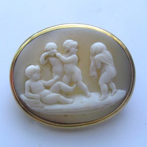 Broche antiguo de querubín con camafeo de concha de putti jugando en oro de 14 quilates