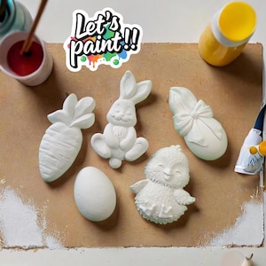 May include: A set of five white ceramic Easter-themed figurines, including a bunny, chick, carrot, egg, and a bunny with a bow. The figurines are ready to be painted. The text "Let's paint!!" is written on a colorful sticker.