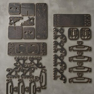 Peut inclure: Ensemble de pièces en bois brun foncé, comprenant des carrés, des rectangles et divers éléments façonnés. Les pièces semblent faire partie d'un ensemble de construction modulaire, avec des découpes et des trous pour l'assemblage. L'ensemble comprend des pièces ressemblant à des prises électriques.