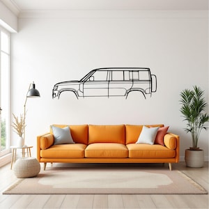 Puede incluir: Arte de pared de metal negro que representa un perfil lateral de un vehículo utilitario deportivo. La obra de arte está montada en una pared blanca sobre un sofá naranja. La habitación también cuenta con una lámpara de pie, una mesa auxiliar y una planta en maceta. El sofá mide 2,4 metros de largo.