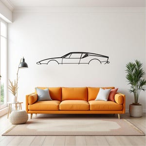 May include: A black metal wall art piece depicting the side profile of a classic sports car. The artwork is mounted on a white wall above an orange sofa. The room also features a floor lamp, a side table, and a potted plant.