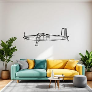 May include: A black and white line drawing of a small airplane on a white wall above a teal and yellow sofa with a gray ottoman. The sofa is in a living room with a green plant in a woven basket and a gray plant in a woven basket.