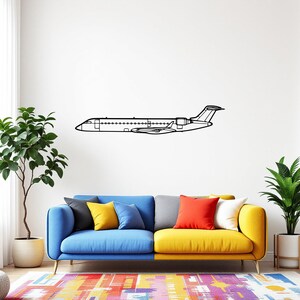 May include: A black metal airplane wall art piece is mounted on a white wall above a colorful sofa. The airplane is a side profile outline with detailed features. The sofa has blue, yellow, and gray sections with colorful pillows. A patterned rug is on the floor.